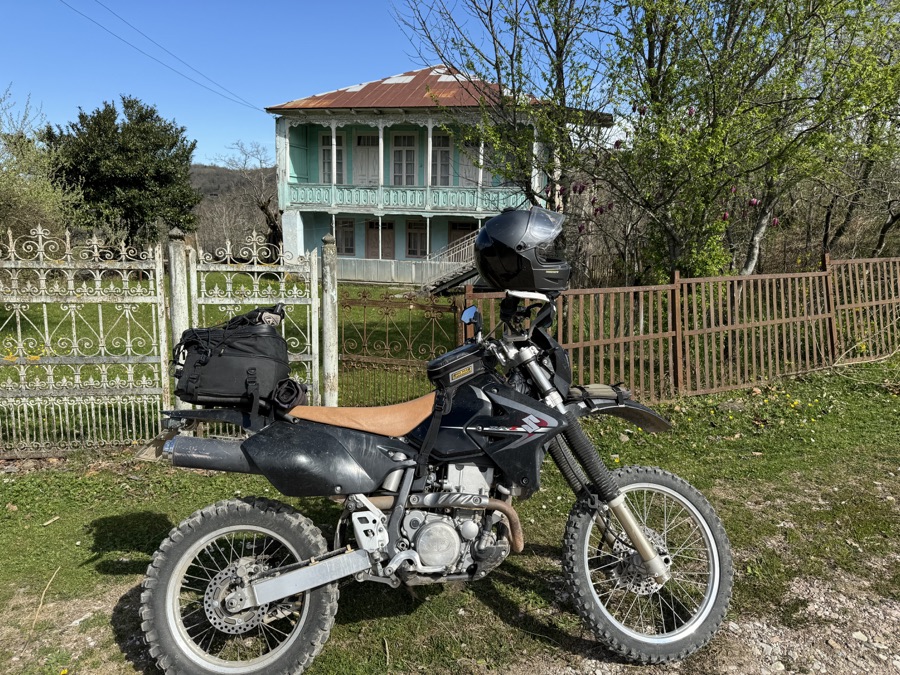 Suzuki DR-Z400S parked beside a traditional Georgian house